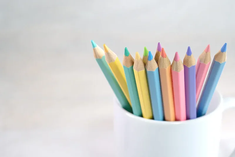 Colored pencils in coffee mug in front of bright background