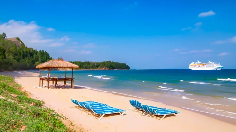 A photo of a beach with lounge chairs and a cruise ship in the background