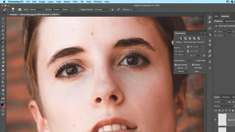 Close-up of a person's face in Adobe Photoshop CC 2018 at 200% zoom, showing a circular Healing Brush cursor positioned near the right eye alongside the Clone Source options panel.