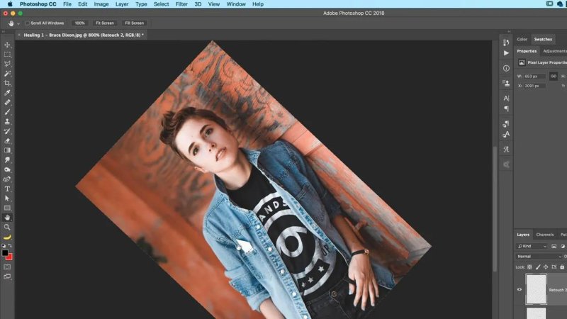 Photoshop workspace showing a portrait photo angled dynamically with the Rotate View Tool compass widget active near the model's denim jacket.