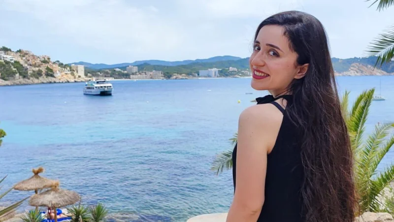 BYOL member Ban Khasawneh smiles at the camera in front of an ocean