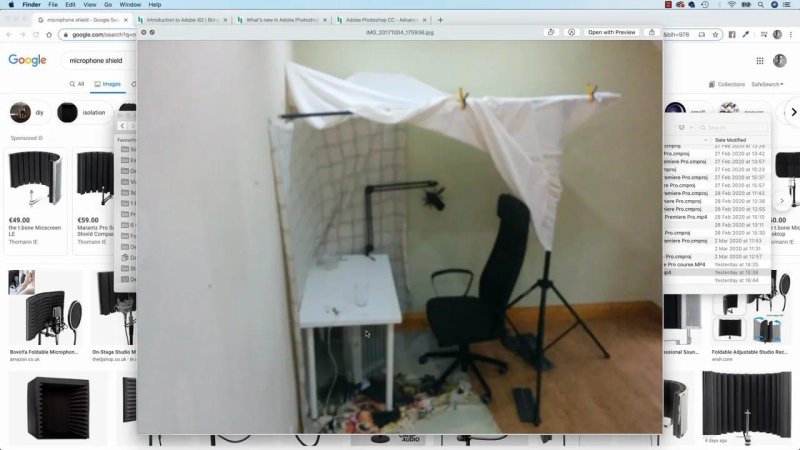 Photo of a DIY home recording booth made of white sheets draped over lighting stands around a desk and chair.